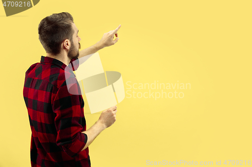 Image of Half-length close up portrait of young man on yellow background.