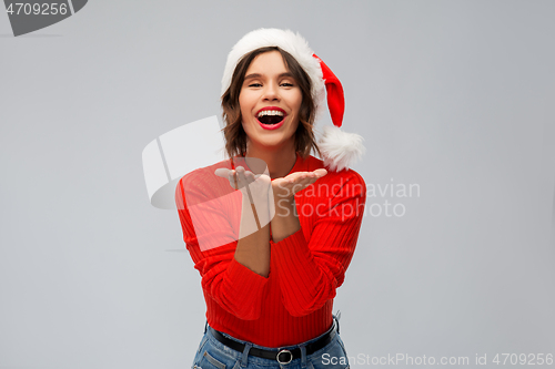 Image of happy young woman in santa hat sending air kiss