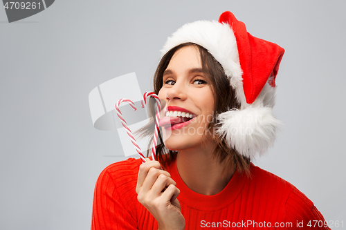 Image of woman in santa hat licks candy canes on christmas