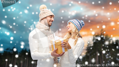 Image of smiling couple in winter clothes with gift box