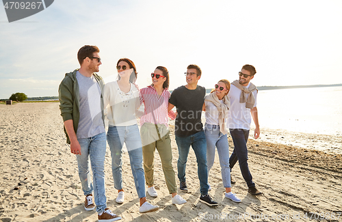 Image of happy friends walking along summer beach