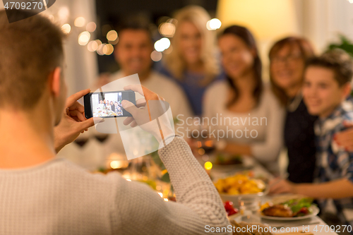 Image of man taking picture of family at dinner party