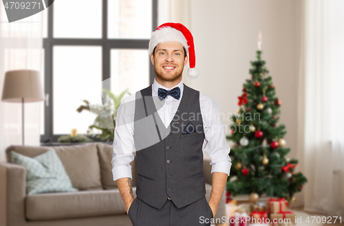 Image of man in santa hat and suit at home on christmas