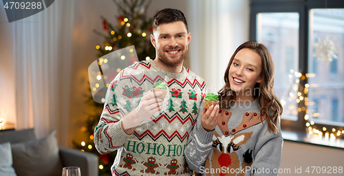 Image of couple with cupcakes in ugly christmas sweaters