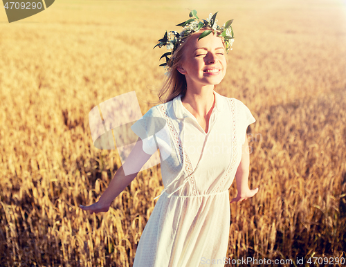Image of happy young woman in flower wreath on cereal field
