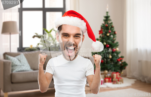 Image of man in santa hat celebrating victory at home