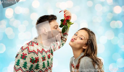 Image of happy couple kissing under mistletoe on christmas