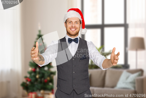 Image of happy man in santa hat holding something imaginary