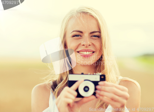 Image of happy young woman with film camera outdoors
