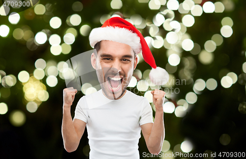 Image of man in santa hat celebrating victory at home