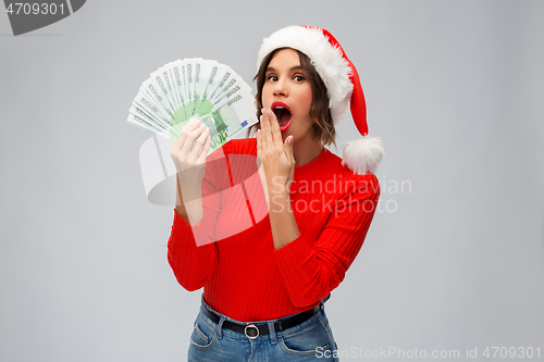 Image of surprised woman in santa hat with money