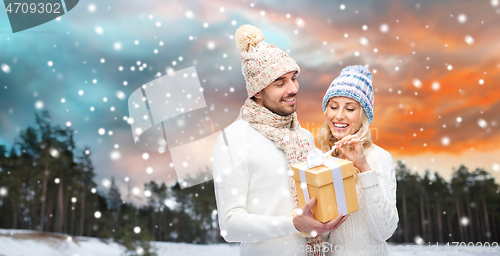 Image of smiling couple in winter clothes with gift box