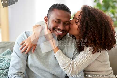 Image of happy african american couple kissing at home