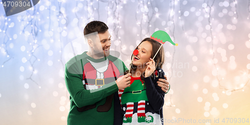 Image of couple with christmas party props in ugly sweaters