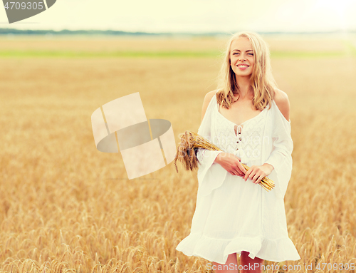 Image of happy young woman with spikelets on cereal field