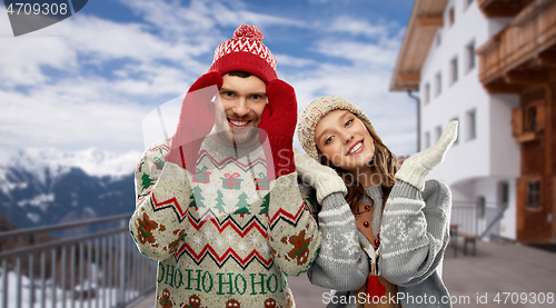 Image of couple in ugly christmas sweaters over ski resort