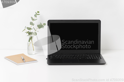Image of laptop with black screen on white office table