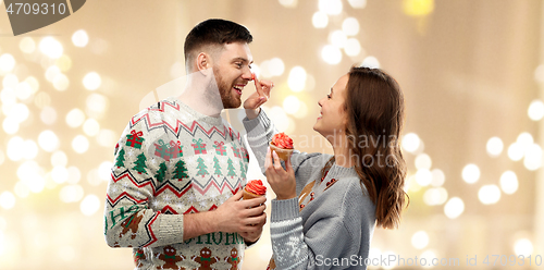 Image of couple with cupcakes in ugly christmas sweaters