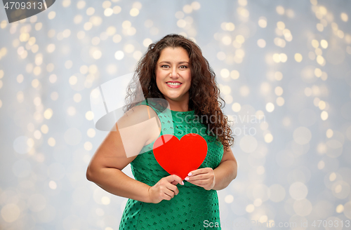 Image of happy woman holding red heart over lights