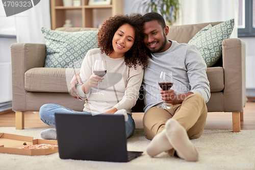 Image of happy couple with laptop drinking red wine at home