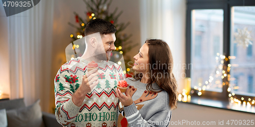 Image of couple with cupcakes in ugly christmas sweaters