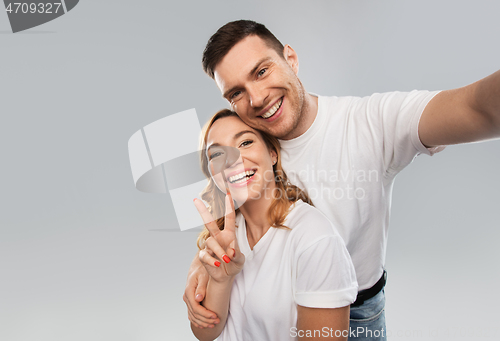 Image of happy couple in white t-shirts taking selfie