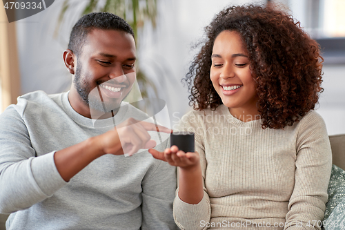 Image of african american couple with smart speaker at home