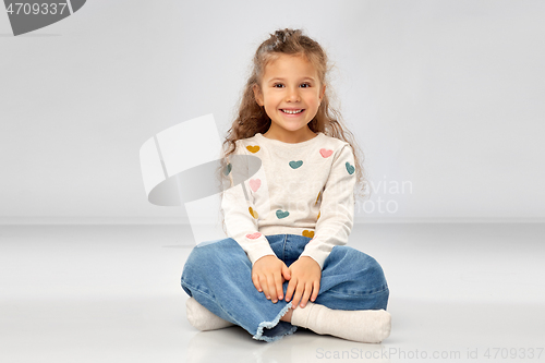 Image of beautiful smiling girl sitting on floor