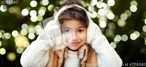 Image of happy little girl in earmuffs over winter forest