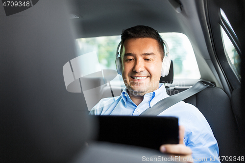 Image of passenger with headphones using tablet pc in car