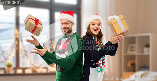 Image of happy couple in christmas sweaters with gifts