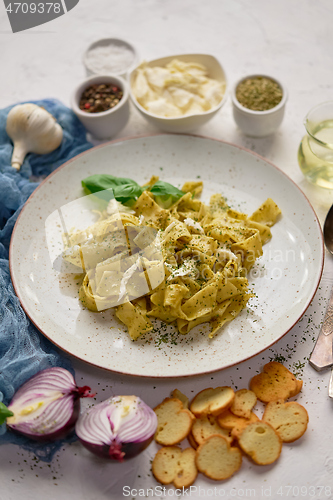 Image of Cooked homemade pasta with pesto, fresh basil, mozarella cheese and herbs