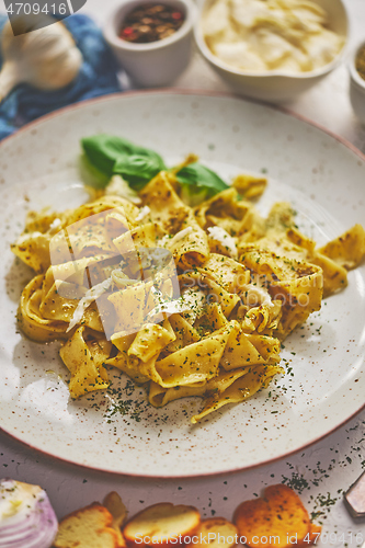 Image of Cooked homemade pasta with pesto, fresh basil, mozarella cheese and herbs