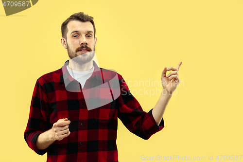 Image of Half-length close up portrait of young man on yellow background.