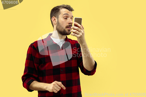 Image of Half-length close up portrait of young man on yellow background.