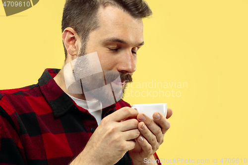 Image of Half-length close up portrait of young man on yellow background.