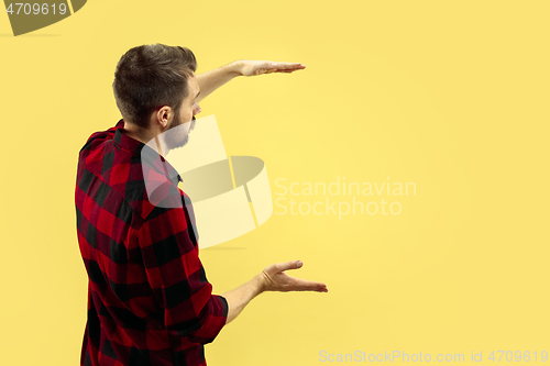 Image of Half-length close up portrait of young man on yellow background.