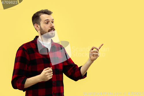 Image of Half-length close up portrait of young man on yellow background.