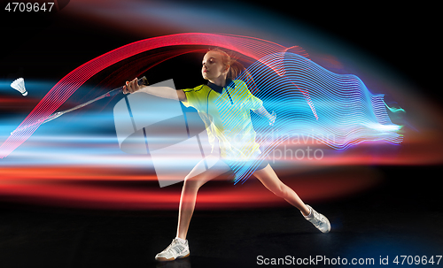 Image of Young girl playing badminton over dark background