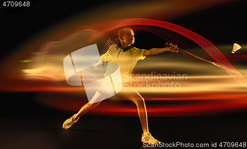 Image of Young girl playing badminton over dark background