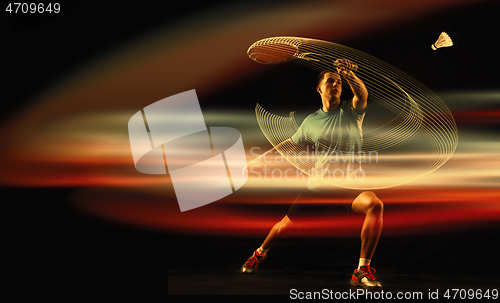 Image of Young man playing badminton over dark background