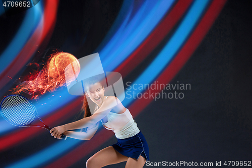 Image of Full length portrait of young woman playing tennis on dark studio background