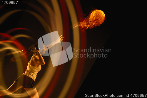 Image of Full length portrait of young woman playing tennis on dark studio background