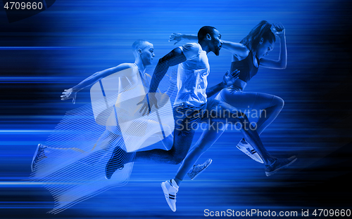 Image of Young african-american and caucasian men and woman running isolated on blue studio background