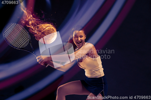 Image of Full length portrait of young woman playing tennis on dark studio background