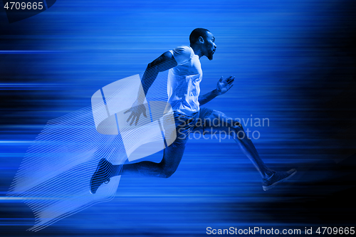 Image of Young african-american man running isolated on blue studio background
