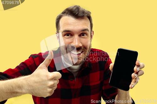 Image of Half-length close up portrait of young man on yellow background.