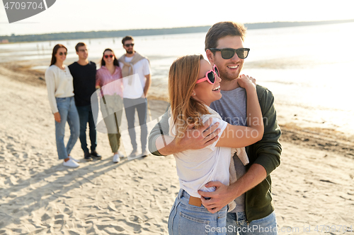 Image of happy couple and group of friends on summer beach