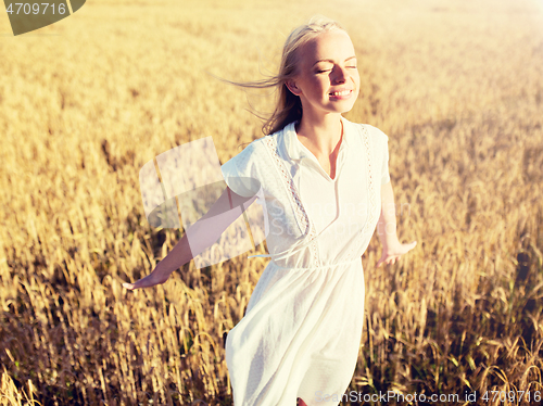 Image of smiling young woman in white dress on cereal field