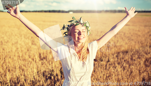 Image of happy young woman in flower wreath on cereal field